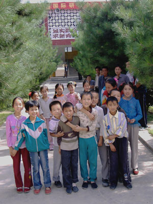 Group of children in Gansu province photographed on a tree-lined avenue. 