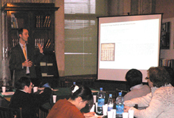 Man standing next to a projector screen, giving a talk.