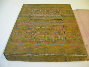 Rectangular book cover closed, highlighting the pattern of the silk cover and the geometric shape on the lid.