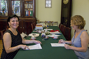 Susan Whitfield and Irina Popova sitting opposite each other at a table while signing a memorandum of understanding.
