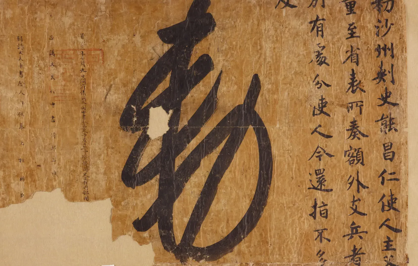 Close up of a Chinese character painted on brown paper fragment and smaller characters to the right