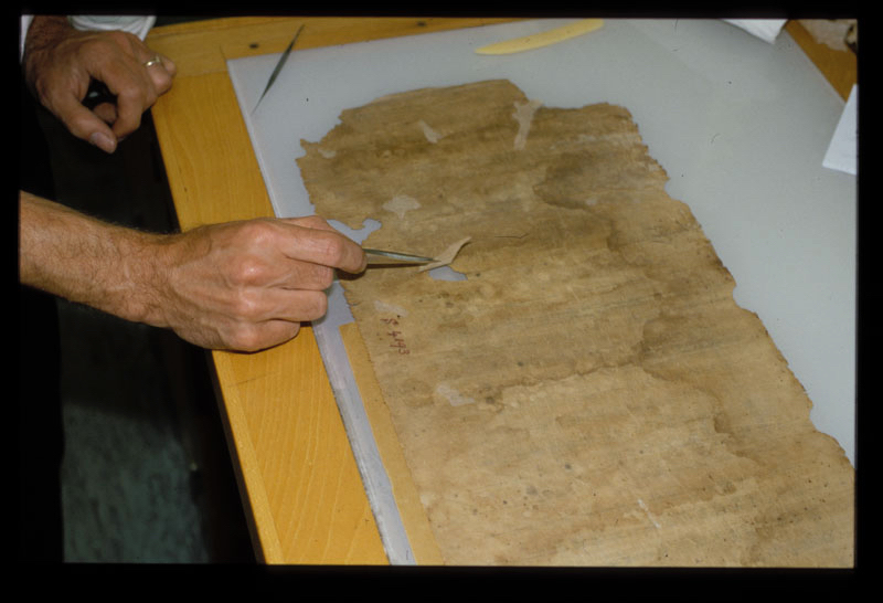 Pasting a small piece of Japanese paper to repair a missing area of the scroll.