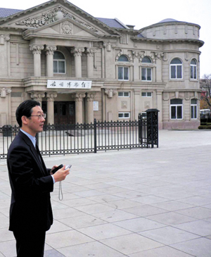 A man in a suit outside a museum built in a Western neoclassical style.