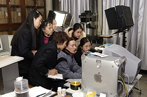 Colleagues gathered around a computer monitor.