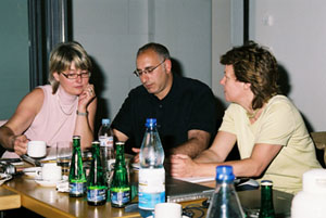 Three colleagues at a table with water bottles and notes.
