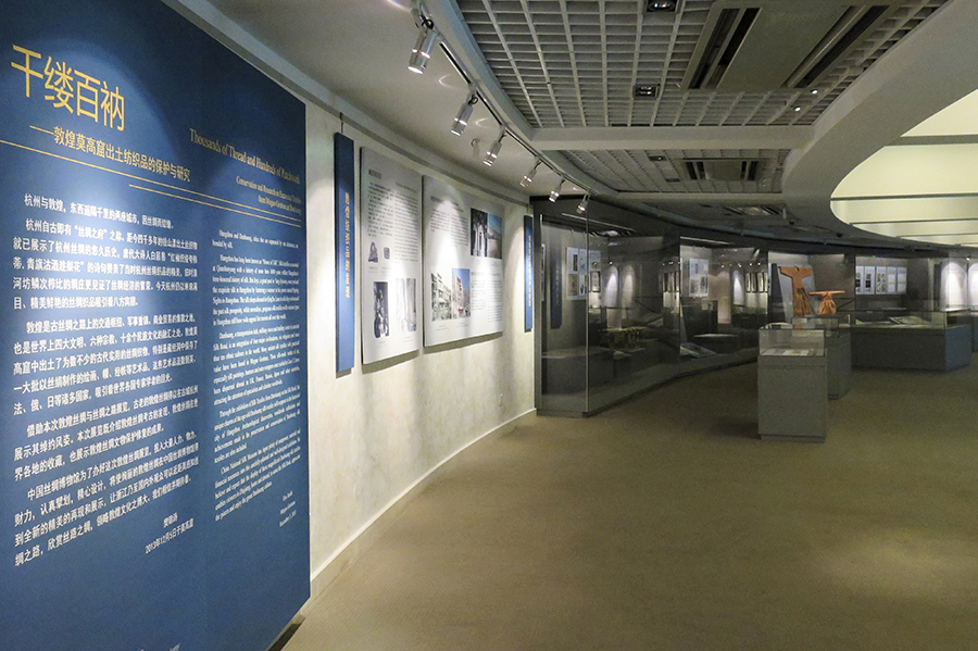 An indoor museum space with an exhibition about textiles set up in cases.