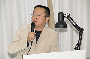 Headshot of Luo Huaqing with a microphone, giving a talk.