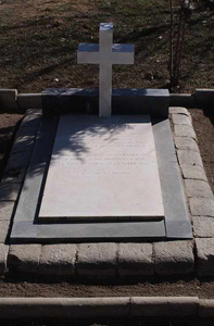 A flat inscribed gravestone with a cross above it.