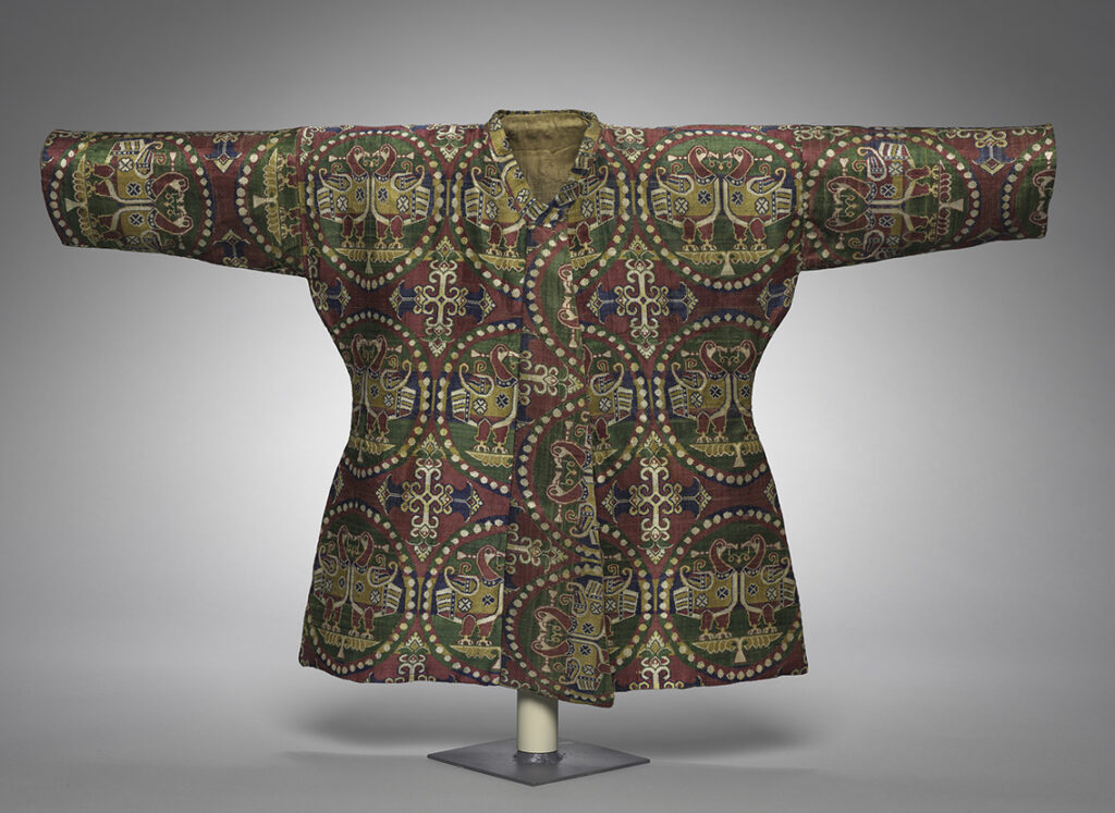 Lavishly embroidered coat for a child, hung on a display form. 