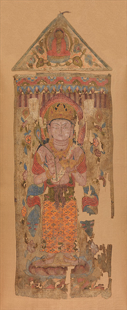 Brightly coloured silk banner, partly damaged, with a bodhisattva in the middle. .