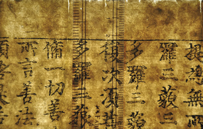 Upper edge of a panel of the Diamond Sutra photographed on a lightbox so that the fibres of the paper are as visible as the printed text. 
