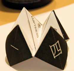 Paper folded in the shape of a paper fortune teller with Chinese characters for numbers on the outer faces. 