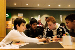School aged young people at a desk engaged in conversation.