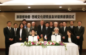 Posed photograph of colleagues displaying the signed Memorandum of friendship and cooperation. 