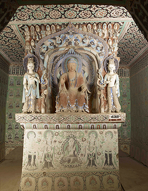 Intricately carved and brightly painted pillar with statues of a seated Buddha and standing bodhisattvaes.