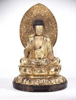 A metal sculpture of the Buddha seated and surrounded by a halo.