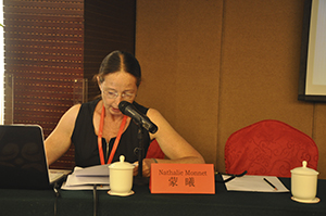Nathalie Monnet seated at a desk, presenting a paper at a conference. 