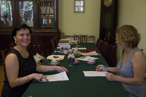 Irina Popova and Susan Whitfield opposite one another at a table with documents for signing between them. 