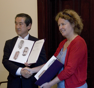 Dosho Wakahara and Susan Whitfield shaking hands and displaying a signed agreement.