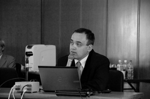 Black and white photograph of Imre Galambos presenting a symposium paper.