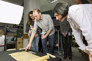 Colleagues demonstrating a partially unrolled Chinese manuscript scroll. 