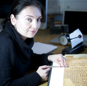 Headshot of Agnieszka Helman-Ważny with a scroll unrolled on a lightbox for study.