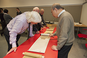 People looking at partially unrolled Chinese manuscript scrolls. 