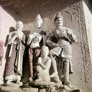 Group of statues of human forms, including a guardian deity, bodhisattva, and monk.