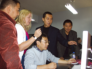Colleagues gathered around a computer monitor during digitisation training. 