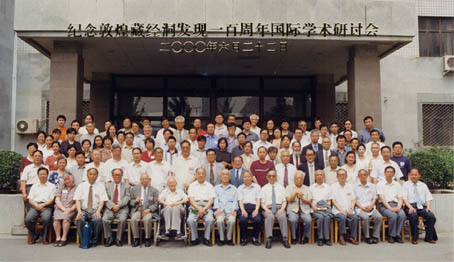 A posed photograph of a large group, in front of a university building entrance. 