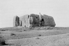 Black and white historic photograph of a ruined watchtower in the desert. 