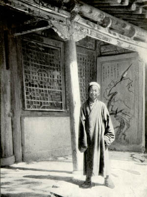Wang Yuanlu standing in the verandah of a temple space. 