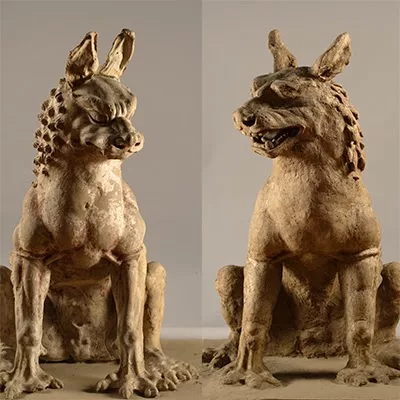 Two statues of guardian animals, sitting, looking very dog-like. 