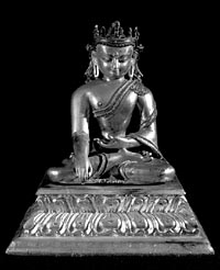 Tibetan metal sculpture of a religious figure, photographed against a black background. 