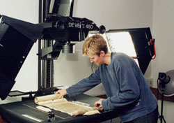 A colleague placing a scroll on the platform surface underneath a digitisation camera.