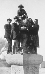 A group of men standing on a pillar.