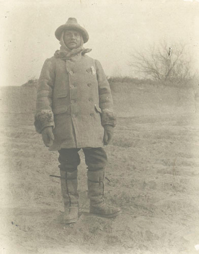 A man standing in cold weather gear. Black and white historical photograph. 